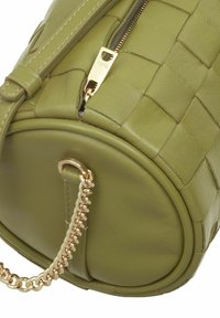 Borsa a tracolla in pelle intrecciata verde con base circolare, tracolla in catena dorata e zip dorata. Presenta un design testurizzato e accenti lisci.