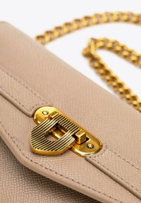 Borsa in pelle beige con una chiusura in metallo dorato dal superficie testurizzata e una tracolla a catena. Il design include dettagli di cucitura.