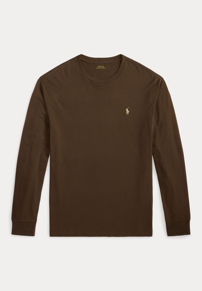 Brūna garām piedurknēm kreklu ar apaļu kakla izgriezumu, uz kreisās krūts ir mazs izsistais Polo Ralph Lauren logo uz baltas fona.