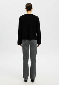 Czarny sweter z długim rękawem, wykonany z miękkiego materiału, połączony z szarymi dżinsami o wysokim stanie i prostych nogawkach. Prosty design, minimalne detale.