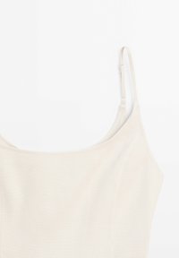 Haut beige sans manches avec un col arrondi. Confectionné dans un tissu lisse, il présente des bretelles fines ajustables et des coutures discrètes.