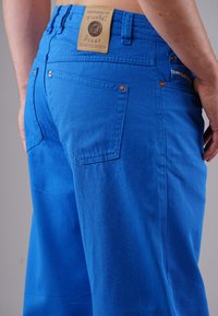 Helle blaue Baumwolljeans mit enger Taille, zwei Gesäßtaschen und kupfernen Nieten. Verfügt über ein braunes Lederlabel am Bund.