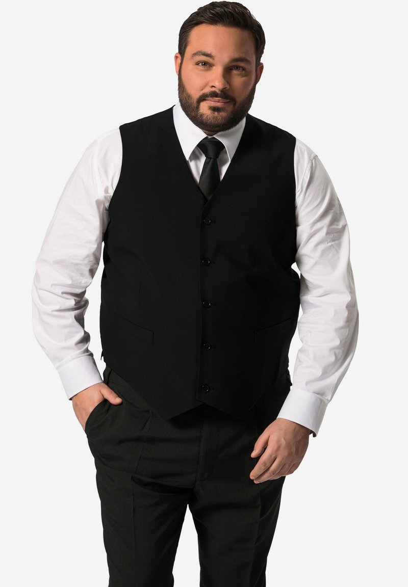 Svart väst med fem knappar, bärs över en vit skjorta och svart slips, kombinerad med svarta byxor med sidfickor.