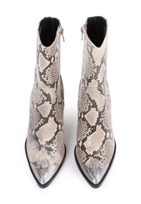 Para beżowo-czarnych botków z wężowej skóry o wysokości kostki, z ostrymi czubkami i dekoracyjnymi srebrnymi metalowymi nakładkami.