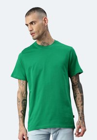 T-shirt in cotone verde con un classico scollo rotondo e maniche corte; presenta una vestibilità rilassata e una consistenza liscia.