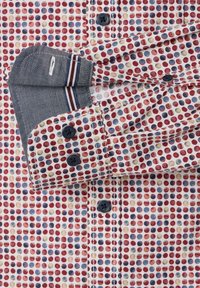 Multicolored shirt with a pattern of red, blue, and yellow dots. Features a contrasting gray cuff with striped accent and dark buttons.
