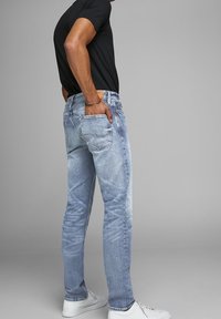 Ljusblå denimjeans med en urtvättad look, rak bendesign, två bakfickor, kombinerade med en svart t-shirt och vita sneakers.