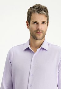 Camicia button-up di un leggero colore viola, con tessuto testurizzato, colletto classico e sei bottoni coordinati. Design elegante e semplice.