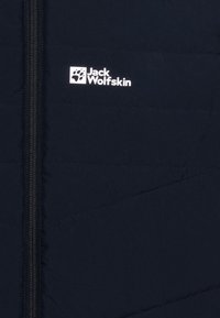 Tummansininen toppatakki, jossa on viistosti ommeltu kuvio, keskellä vetoketju ja valkoinen logo vasemmassa yläkulmassa.