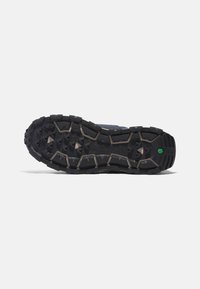 Trailrunningschuhsohle aus schwarzem Gummi mit aggressiven Profilmustern. Verfügt über strapazierfähige Traktionsnoppen und einen verstärkten Fersenbereich.