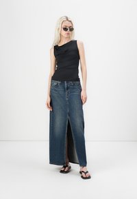 Svart utenermet topp med rynket design, kombinert med et langt, delt front denim skjørt og svarte flip-flops. Jevn tekstur, avslappet antrekk.