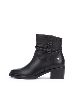 Black leather ankle boot with a slouchy design, rounded toe, and a low block heel. Features stitched detailing and a small gold accent.