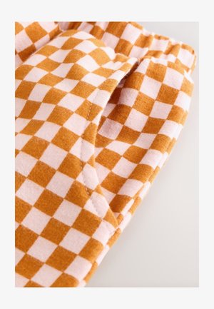 Bombažno blago z oranžnim in belim karo vzorcem. Podrobnosti vključujejo vidni žep in mehek otip.