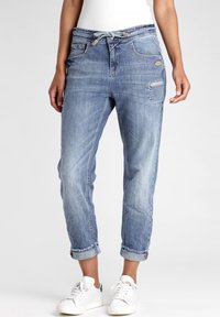 Vaaleansiniset farkut rentoa tyyliä, joissa on käännetyt lahkeet, etutaskut ja kulutetut yksityiskohdat lisäämään rakennetta.