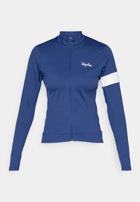 Casaco de ciclismo azul-marinho feito de tecido elástico, apresenta um colarinho alto, mangas longas, fecho de correr completo e detalhe em faixa branca na manga esquerda.