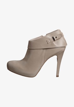 Botte de cheville à talons hauts beige en cuir lisse, avec un large col et une sangle ajustable, dotée d'un bout pointu.