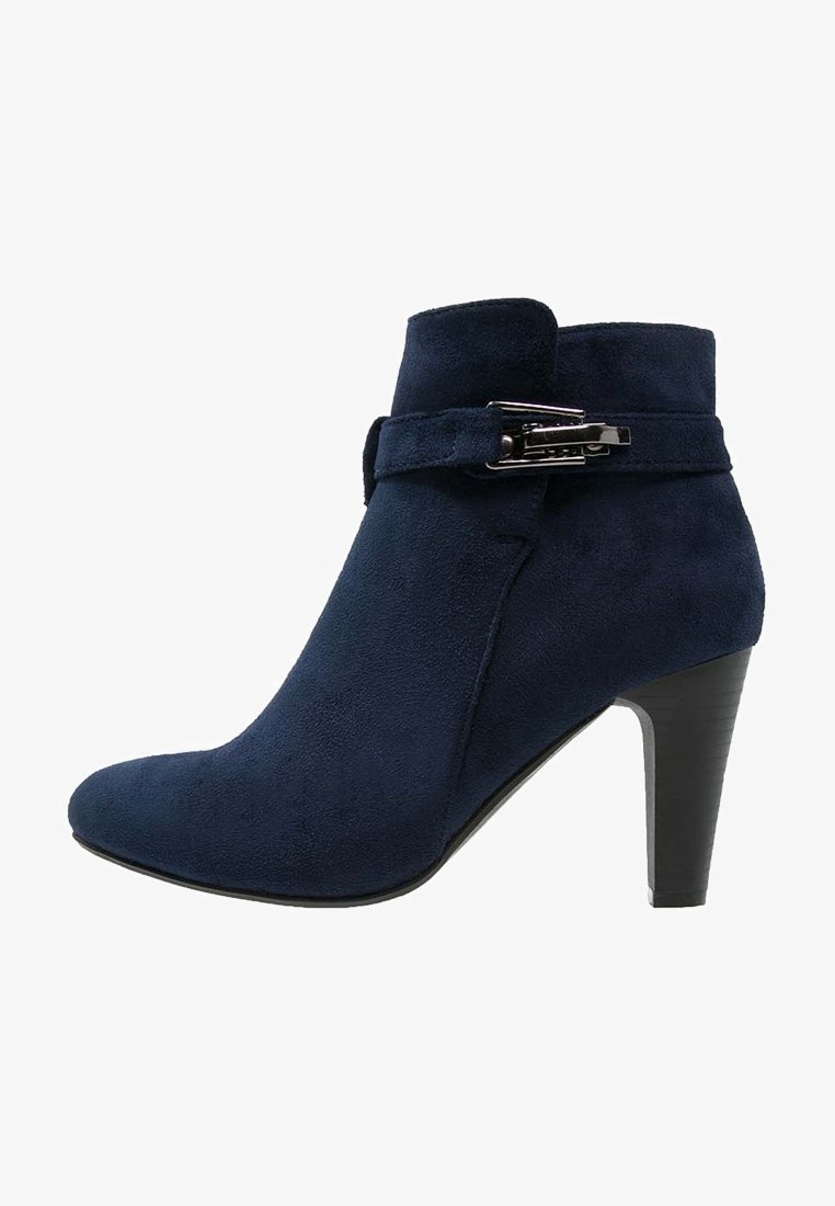 Bottine en daim bleu marine avec un talon moyen empilé et une bride décorative avec boucle métallique.
