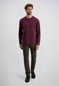 Bordeaux langemouwen trui, ronde hals, gestructureerde stof, gecombineerd met bruine slim-fit broek en zwarte schoenen op een neutrale achtergrond.