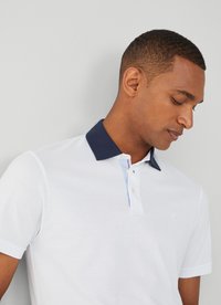 Biela polo košeľa s krátkym rukávom, modrým golierom, so svetlomodrým zapínaním s pruhom a malým logom na hrudi.