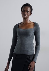 Gray ribbed long-sleeve sweater with a square neckline and slim fit. Soft texture, featuring detailed stitching along the bodice.