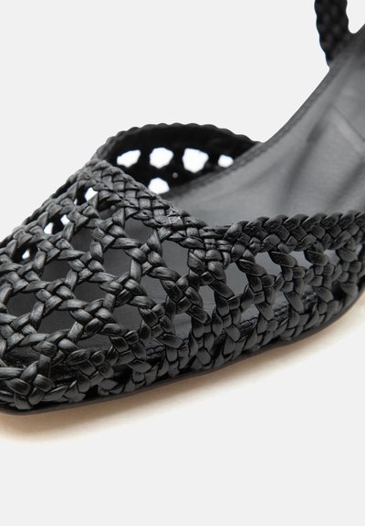 Mustast punutud nahast madalad sandaalid avatud varbaosaga ja punutud rihmadega, mis moodustavad ees ja külgedel võrgustiku mustri.