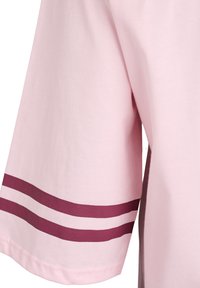 Svetloružová košeľa s krátkym rukávom a rovnými strihmi, s dvoma bordovými horizontálnymi pásikmi na rukáve. Vyrobená z mäkkej, hladkej bavlnenej látky.