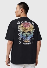 T-shirt en coton noir avec un grand design de crâne coloré composé de divers personnages illustrés et symboles au dos.