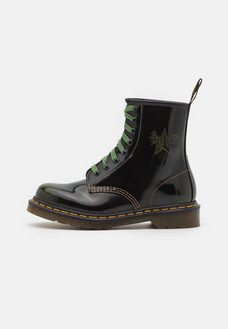Bottine en cuir noir brillant avec lacets verts, couture jaune sur la semelle, et logo étoile brodé sur le côté.