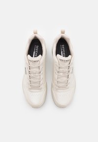 Baskets de sport beiges avec tige synthétique texturée, bout rond et lacets. Logos sur la languette et sur le côté; col rembourré pour le confort.