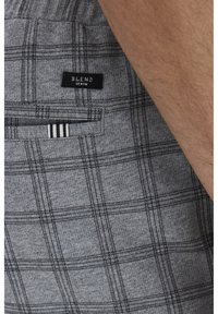 Shorts à carreaux gris en tissu mélangé de coton. Comprend une poche arrière et une étiquette noire avec un texte blanc. Accent en rayures fines noir et blanc.
