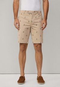 Knee-length beige shorts made from cotton, featuring small green palm tree prints, a flat front, and standard pockets.