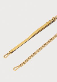 Sárga bőrszíj láncos rögzítéssel, fémes részletekkel és sima, fényes textúrával. A dizájn funkcionális és robusztus.