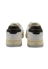 Sneaker bianche e nere con una tomaia in pelle testurizzata, collare imbottito e dettagli del logo sul tallone. Suola in gomma con leggere scanalature per la trazione.