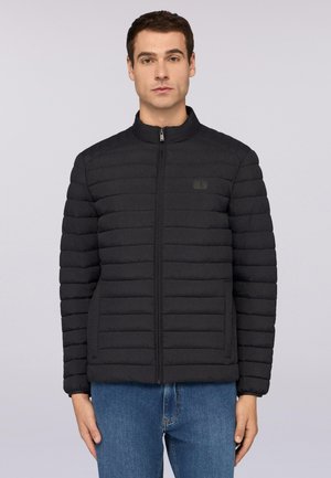 Giacca nera trapuntata con colletto alto, cerniera frontale e branding discreto. Tessuto liscio con linee orizzontali e tasche laterali.