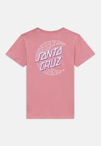 Rožinė medvilninė marškinė su trumpomis rankovėmis. Nugarėlėje yra balta ir violetinė "SANTA CRUZ" logotipas apskritimo grafiniame dizaine.