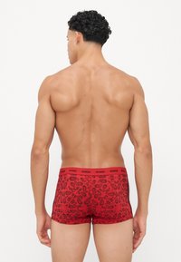 Boxers rouges avec un motif paisley, fabriqués en matière extensible. Présentent une ceinture élastique rouge avec le logo 'DIESEL'.