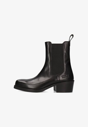 Stivale alla caviglia in pelle nera con pannelli elastici laterali, punta rotonda, tacco leggero e linguetta sul retro; superficie liscia con branding minimo.