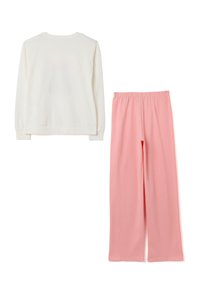 Un haut blanc à manches longues associé à un pantalon rose ample taille haute, posé à plat sur un fond blanc.