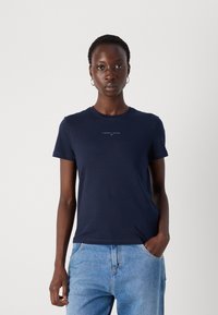 T-shirt in cotone blu navy con maniche corte, colletto rotondo e piccolo logo bianco "TOMMY JEANS" al centro. Texture liscia.