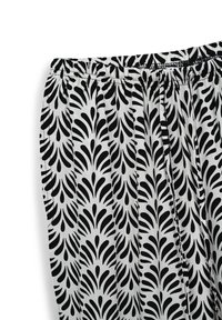 Tessuto a motivo a goccia in bianco e nero. Fascia elastica in vita, texture liscia e materiale morbido con dettagli plissettati.