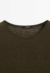 Olivenfarvet kortærmet t-shirt lavet af et blødt, tekstureret stof, med rund halsudskæring og et mærke midt på ryggen.