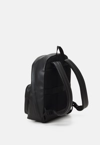 Zaino in pelle nera con schienale in rete imbottita, spallacci regolabili e tasca laterale. Presenta una texture liscia e un design elegante.