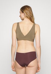 Bralette castanho com decote em V e calcinhas em bordô, feitas de tecido suave. O bralette tem alças largas e um design sem costuras, proporcionando uma aparência suave.