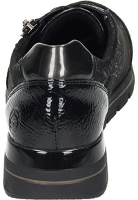 Zwarte sneaker met een gestructureerde bovenkant, glanzende lakleren accenten en een slanke, ronde hak. Stevige rubberen zool voor grip.