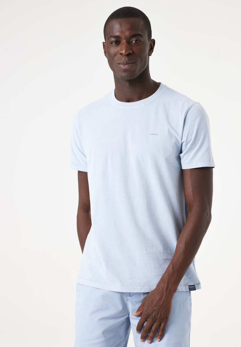 Camiseta de algodón azul claro con cuello redondo y mangas cortas. Presenta un pequeño logo en el pecho y un corte relajado.