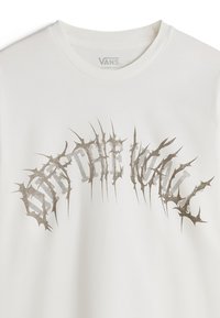 Hvid bomulds T-shirt med et tekstureret, sølvfarvet torn-lignende grafik, der viser teksten "OFF THE WALL" tværs over brystet i et buet design.