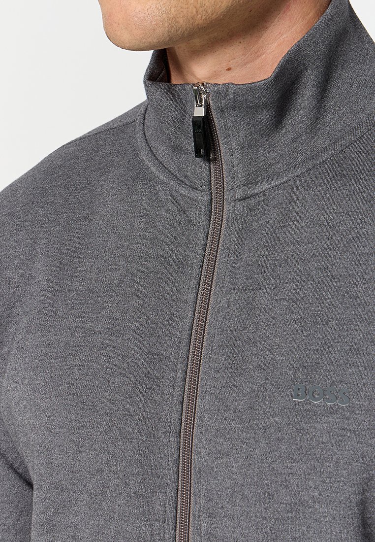 Grijze ritsjack met hoge kraag, met een contrasterende rits en subtiele logo-detail op de borst; gemaakt van zachte stof.