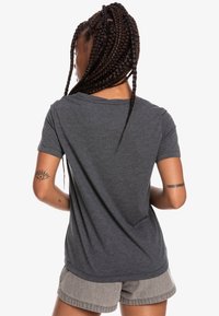 Camiseta gris de manga corta con un escote redondo y textura suave. Presenta un ajuste relajado, costuras sutiles y un diseño sencillo.