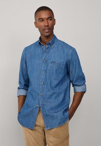 Leren button-up shirt in lichtblauw met een borstzak, opgerolde mouwen en contrasterende knopen. Bevat een klein label op de zak.