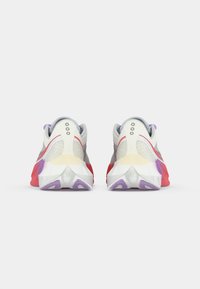 Sneaker con una parte superiore in rete grigia, accenti bianchi e rossi, una suola intermedia texturizzata e una suola colorata con dettagli viola e lavanda.